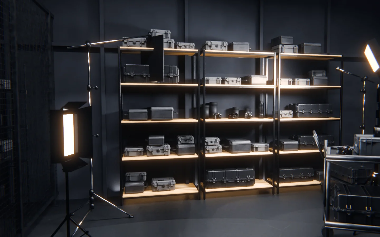 THE CAGE: black steel shelves of black hard cases, camera bodies and lenses, C-stands and a lit panel